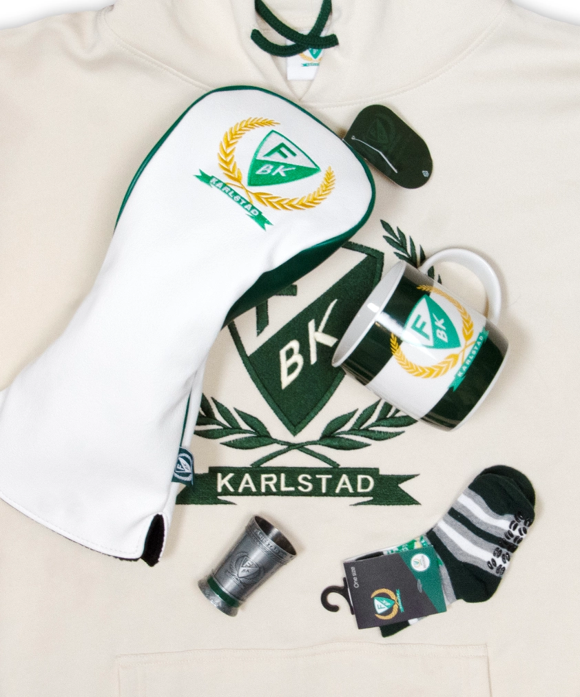 F&auml;rjestad BK merchandise utlagd p&aring; en gr&auml;ddvit hoodie: ett vit- och gr&ouml;nf&auml;rgat golfklubbsfodral, en randig mugg, ett litet snapsglas i metall och ett par randiga strumpor